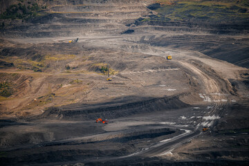 Expansive open pit coal mine with machinery on rugged terrain