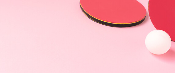 Banner with tennis rackets and white ball on a pink background. Creative ping pong concept.