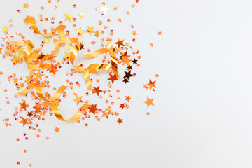 Shimmer golden ribbons, stars and crystals confetti on a blue background. Festive concept with place for text. Selective focus.