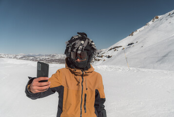 Skier in orange jacket taking selfie on snowy mountain