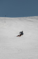 Skier carving turns on a steep slope in winter