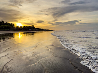 Sunrise Over Ocean Waves with Reflections on Beach
