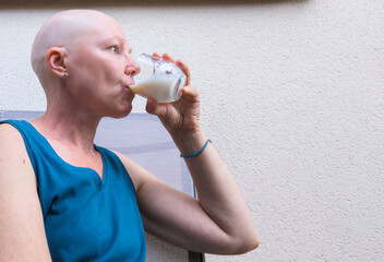 A woman undergoing chemotherapy calmly drinks a glass of milk. A healthy diet is very important...