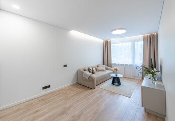 Modern Home Living Room Interior with Open TV Area and TV on the Wooden Desk, Sofa, And Coffee Table. Flowers on the Table. Windows and Curtains in Background. Hardwood Floor, Carpet on the ground