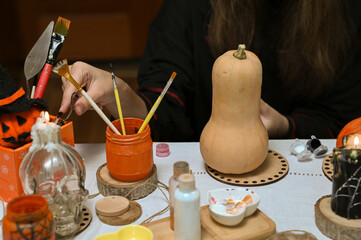 A girl paints a pumpkin for Halloween