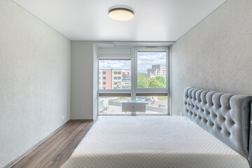 Home Bedroom Interior. King Size Double Bed, Windows and Heater. White Walls and Ceiling. LED Light. Dark Hardwood Floor.