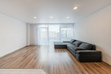 Modern Home Living Room and Windows, Balcony. Luxurious Stylish Modern Apartment. Open Space Interior, Stylish Sofa, Couch. Scandinavian Design. Hardwood Floor