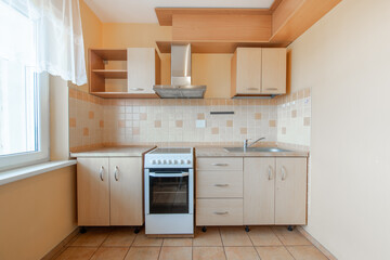 Cozy Wooden Kitchen Home Interior. Oven, Faucet and Furniture in Background. Dark Brown Flooring. Tile Floor