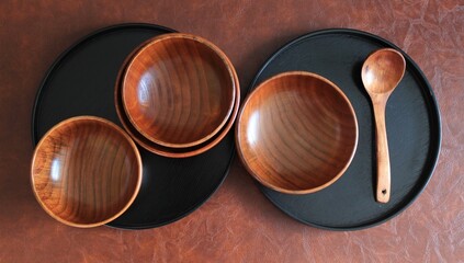 wooden bowls and wooden black plates put on a leather background 
