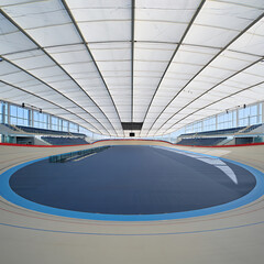 Indoor velodrome with blue track and white ceiling structure