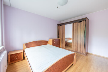 Minimalism Bedroom Interior. Wardrobe and Window in Background. Apartment is Ready for the Rent. White Heater. Old Soviet Style Room Interior. Home Interior. Pink Walls. Wardrobe and Mirror