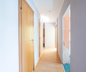 Home Corridor in bad condition. Dirty Room. Old Soviet Russian Poor Interior. Shabby wooden floor. Closed Wooden Door to Bathroom