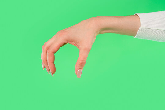 Woman's hand with light skin and manicured nails in a pinching gesture on green backdrop - Powered by Adobe
