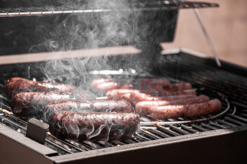 Close-up of steaming and tasty blood sausage and white sausages, cooked over charcoal on the...