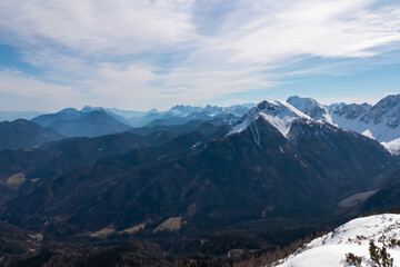 Snow-capped peaks rise above deep valleys, sunlight illuminating the rugged slopes of Kosiak,...