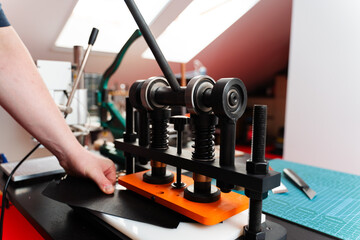 Craftsman uses press machine to imprint patterns into leather. Leather pressing provides strength and detail to handmade designs, creating premium results for wallets, belts, and accessories.