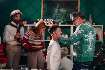 Grandfather caressing grandson's face during christmas family reunion