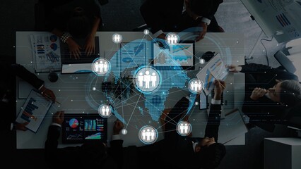 Aerial view of a modern office meeting showcasing professionals collaborating over digital devices with data visualizations symbolizing global communication and teamwork. Raster