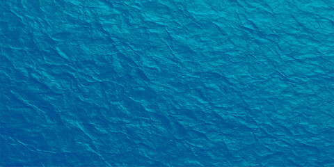An abstract blue wave texture like the clear water of a swimming pool or the ocean surface with ripples and a turquoise reflection