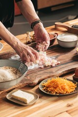 A person prepares Cozonac ingredients on a wooden table. Sweet diced ingredients are being added to a flour mix, with other ingredients such as sugar and shredded orange peel in the background