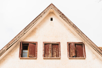 Attic with three rustic windows with wooden shutters. The paint on the windows is very deteriorated by the passage of time. Morning light