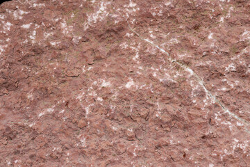 Close-up texture of rough red rock surface with natural patterns and cracks