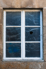 A wooden window, painted white, has one of its six panes of glass missing because a criminal threw a stone at it. Something broken. Psychology