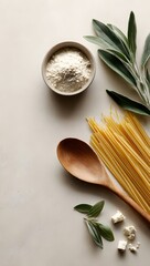 Overhead shot of spaghetti, a wooden spoon, and various fresh ingredients on a light beige background for cooking
