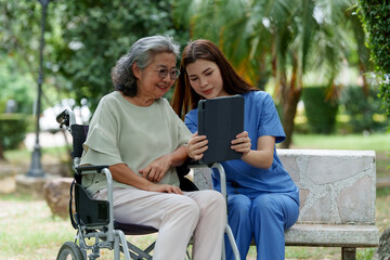 Caring caregiver provides assistance and support to senior while they enjoy moment together outdoors, sharing smile as they engage with tablet