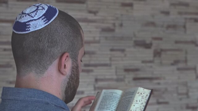 Young Jewish man reading a siddur with a kippah. Middle East.