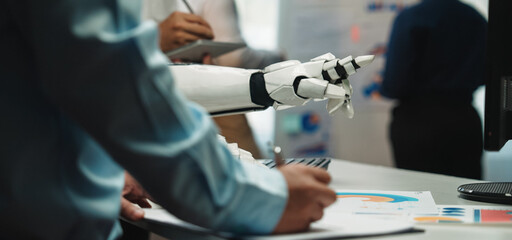 A modern office scene showcasing human and robot collaboration. Professionals engage with technology while presenting data and innovative ideas in a professional environment.Noogenesis