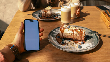 Enjoying cake and coffee at a cafe with a smartphone in hand