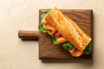 Top view of French baguette sandwich with smashed avocado and smoked salmon, spinach.