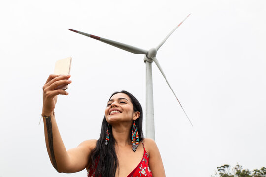 Woman taking selfie with wind turbine in background