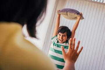 Boy playing with pillow and showing playful mood