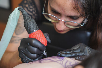 Female tattoo artist focused on creating intricate design