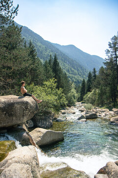 Man sitting on a rock by a stream in the Pyrenees forest