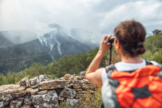 Woman observing forest fires with binoculars in Asturias