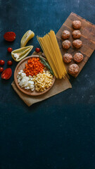 Ingredients for a delicious pasta dish arranged on a dark surface.