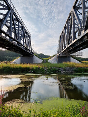 Two parallel bridges bridges over the river. Diminishing perspective view of two old truss over the river.