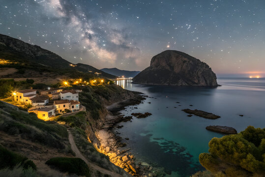 Coastal village under starry night sky with Milky Way and sea stars galaxy