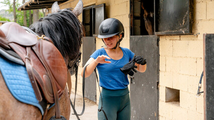 Young woman preparing for horse riding at stable