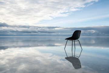 Black modern chair on reflective salt flat under cloudy sky black chair minimalist
