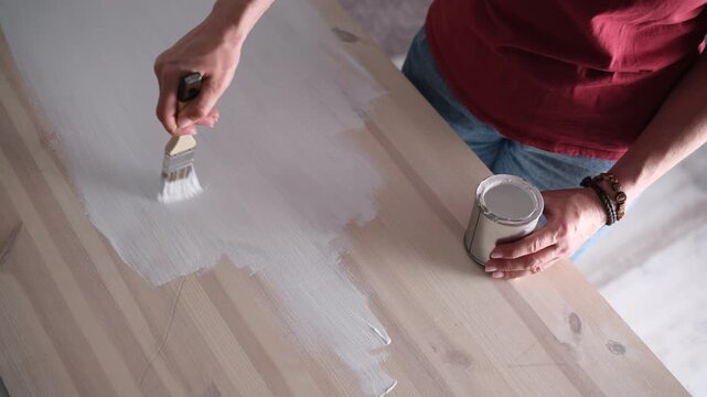Woman Painting Wooden Kitchen Table With Brush From Top View