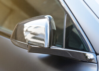 Close-up sport car side mirror black color, modern sport car safety systems. Close up of a black sports car's front fender and door. Folded black gloss rear view mirror classic sport car. 