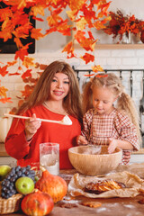 Happy mother and daughter baking together, rolling out dough in a flour-dusted, autumn-themed rustic kitchen with a harvest of fruit and pumpkins. autumn season,  autumn concept,  fall. Halloween. 