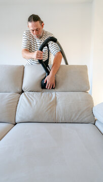 Man cleaning sofa with ionized water machine at home