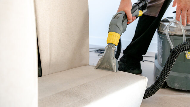 Man cleaning sofa with ionized water machine at home