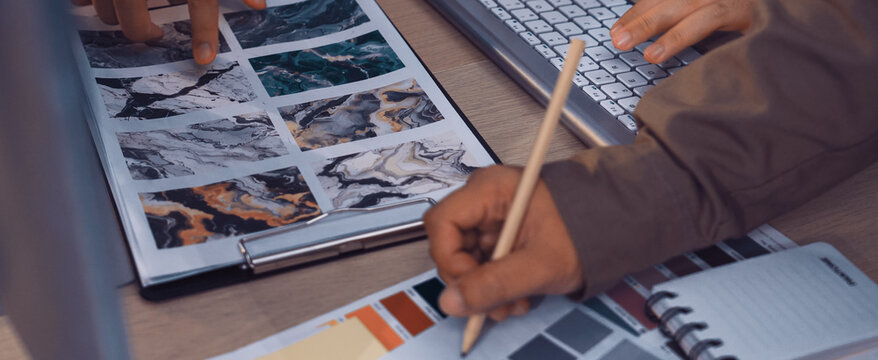 Two hands examine color palettes and texture samples in a collaborative workspace, illustrating creative brainstorming and design strategy with various materials displayed. SACTR