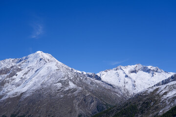 Majestic snow-capped mountains rise against a clear blue sky, showcasing rugged terrain and natural beauty, inviting exploration and adventure in a serene landscape